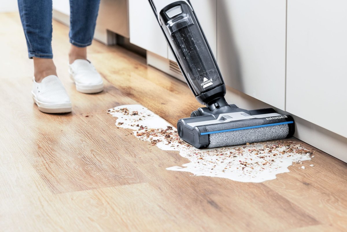 Vacuum cleaner cleaning spill on hardwood floor