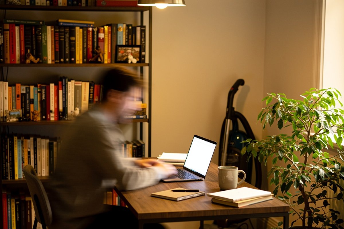 Home office with a laptop and a vacuum cleaner in the background