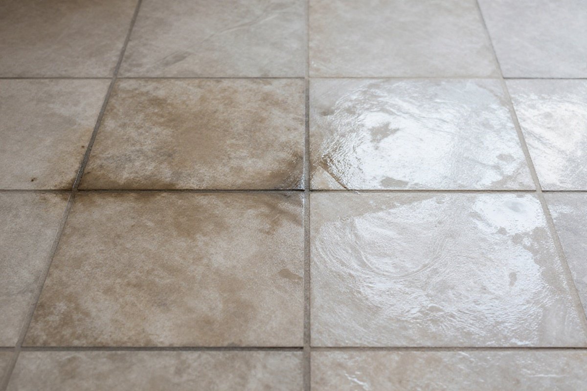 Stone tile floor grout showing dramatic before and after steam cleaning results