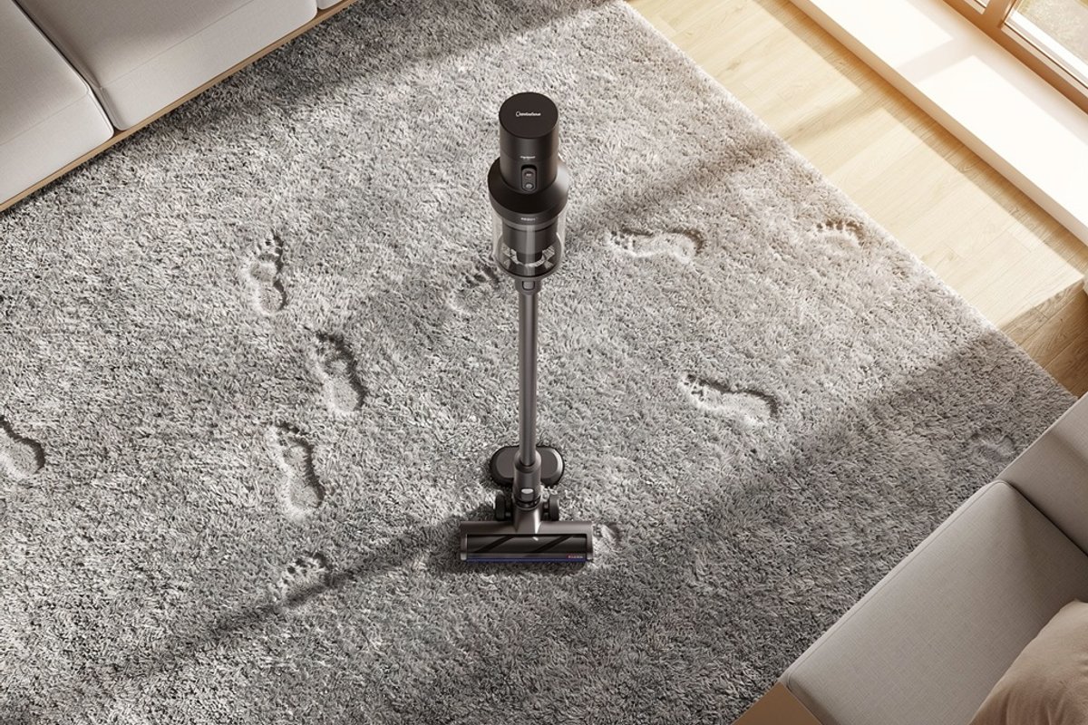 Cordless vacuum standing on a plush gray carpet in a living room