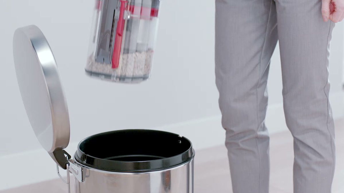 Person emptying Dyson Big Ball Multi Floor Canister into trash can on hardwood floor