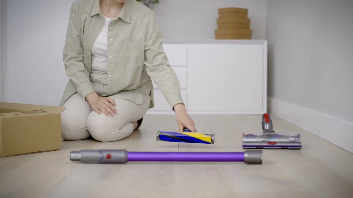 Dyson Gen5detect vacuum accessories laid out on hardwood floor with person assembling
