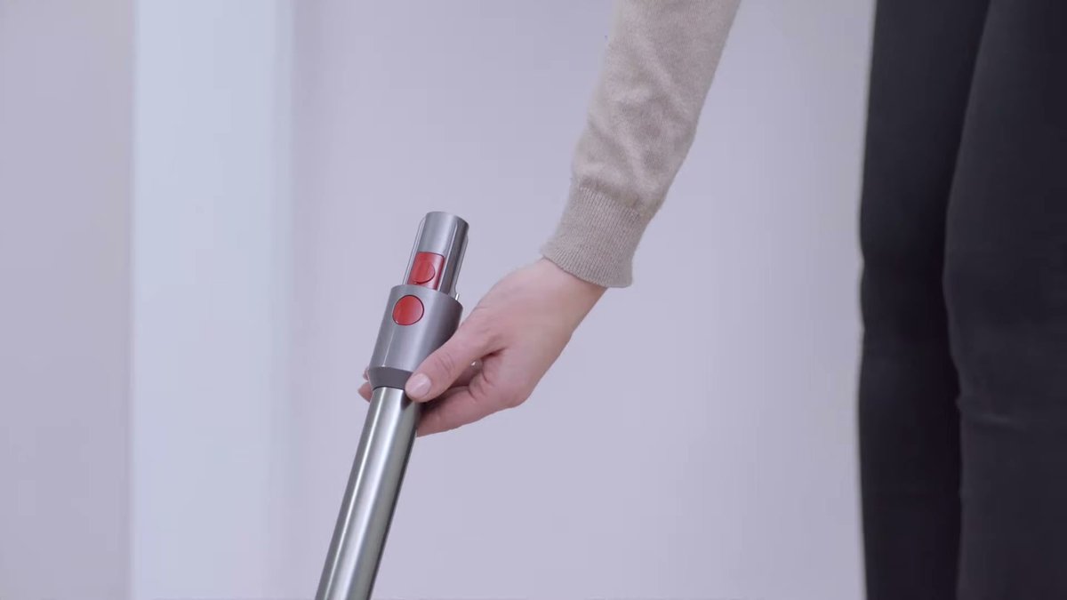Close-up of hand gripping Dyson Omni-Glide handle with red power button visible