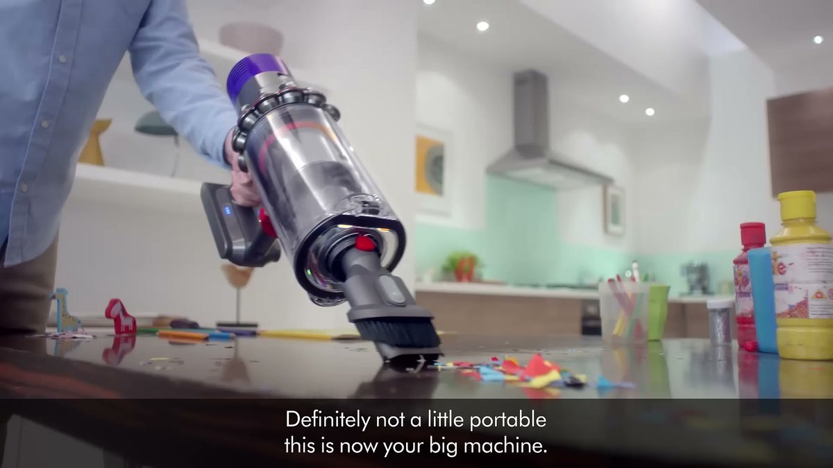 Dyson V10 Absolute (Refurbished/New) being used to clean a kitchen countertop with scattered debris.