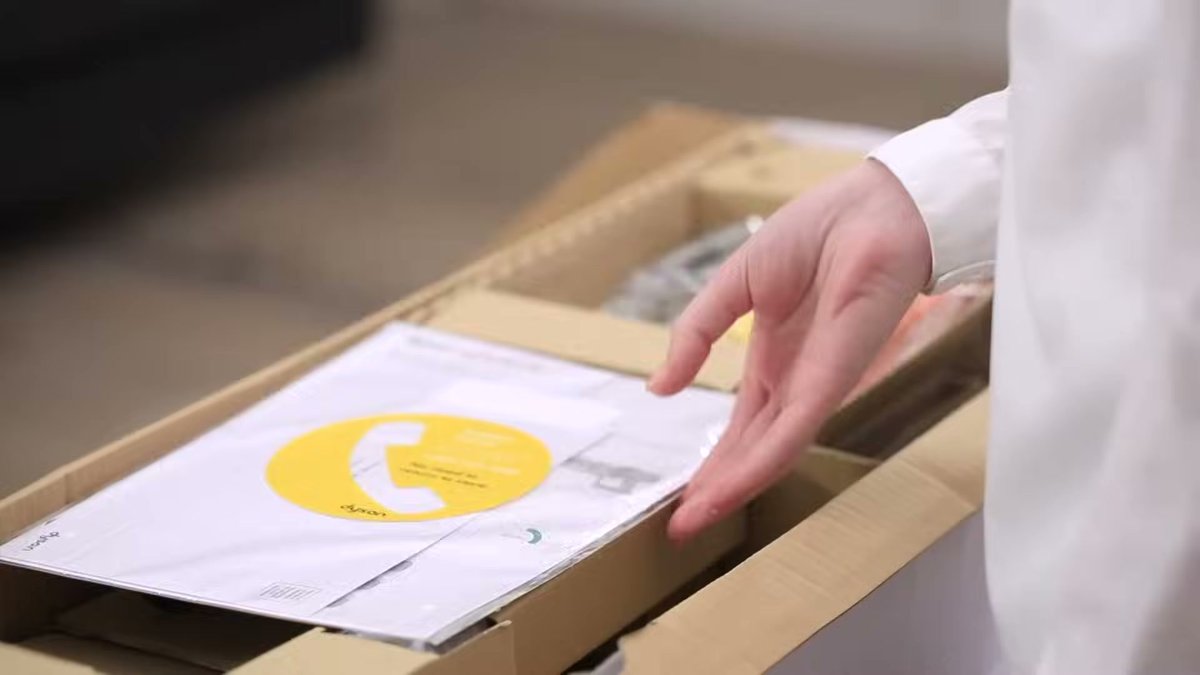 Hand reaching into box with Dyson V10 Absolute documentation and accessories