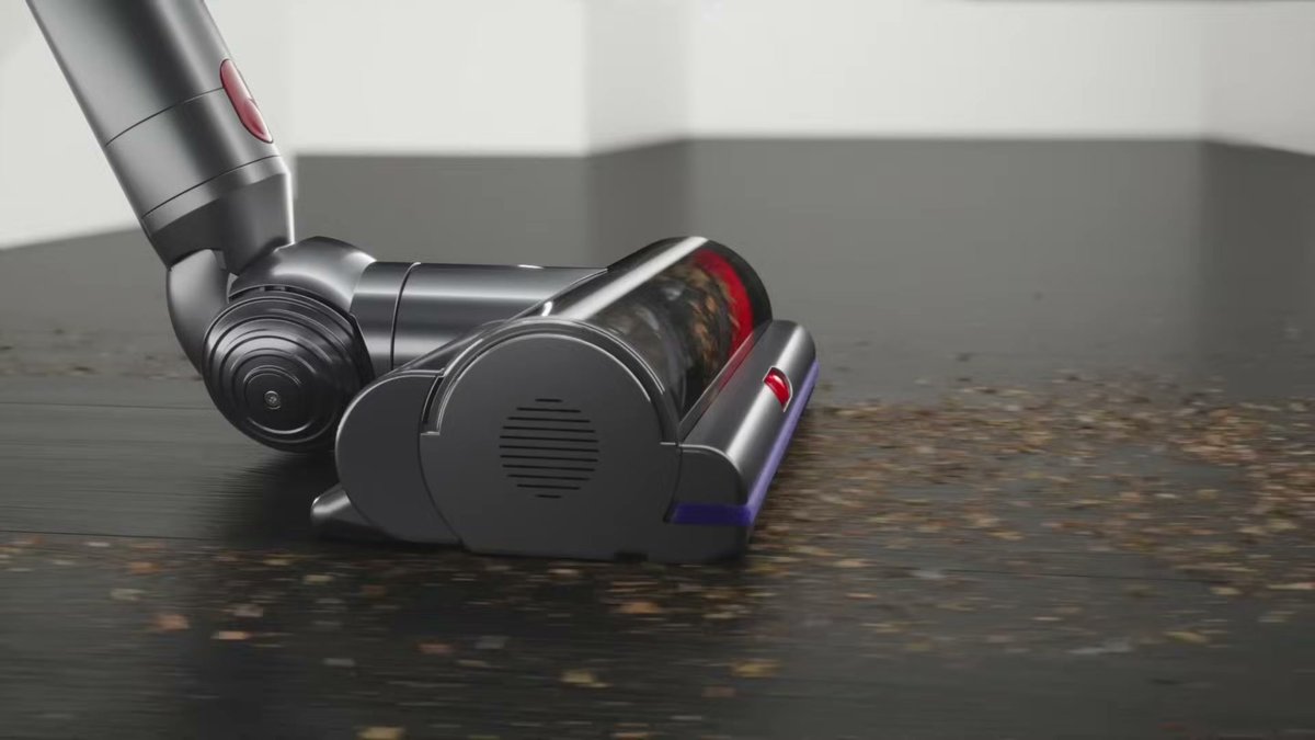 Dyson V15 Detect Absolute vacuum cleaning debris on hardwood floor with laser illumination